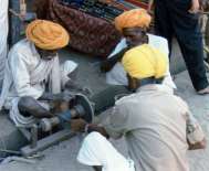 Rajasthanští muži v typických turbanech při broušení nůžek